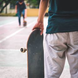 Midsection of man holding skateboard in city