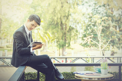 Young woman using mobile phone while sitting on table