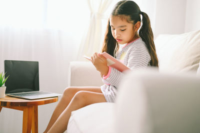 Happy girl sitting on sofa at home