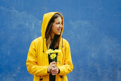 Portrait of young woman standing against wall