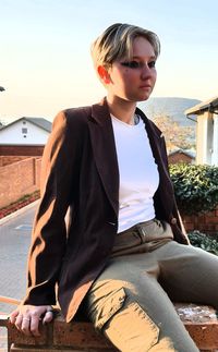 Young woman looking away while sitting against sky