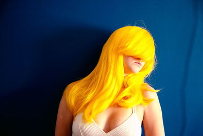 Close-up of young woman against yellow background