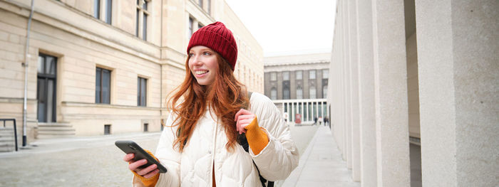 Young woman standing against building