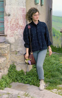 Portrait of young woman standing against wall