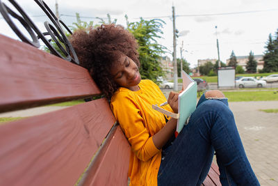 Young woman using mobile phone while sitting outdoors