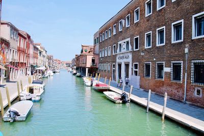 Boats moored in canal amidst buildings in city burano italy