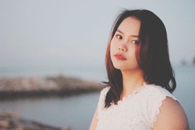 Portrait of beautiful young woman standing against sky