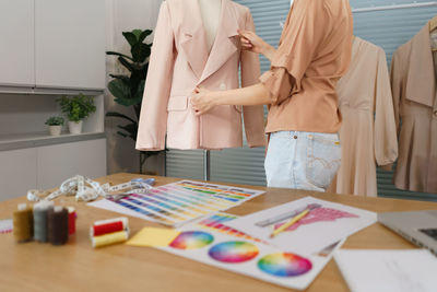 Fashion design concept, asian female tailor is checking quality completeness of suit on mannequin.