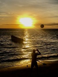 Silhouette person on beach against sky during sunset