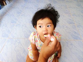 Cropped hand of mother feeding daughter at home