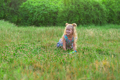 Little girls play in the summer on a green meadow with water pistols