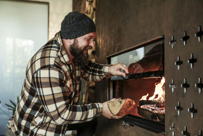 Happy bearded man in front of fireplace at home