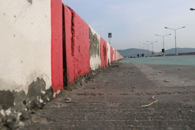 Surface level of road by wall against sky