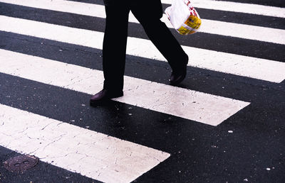 Low section of person walking on zebra crossing