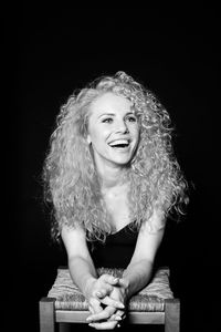 Portrait of smiling young woman against black background