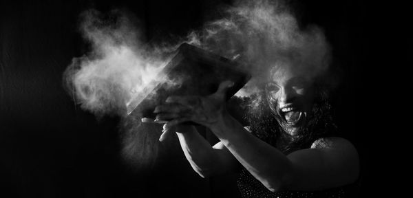 Woman playing with book against black background