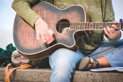 Low section of man playing guitar