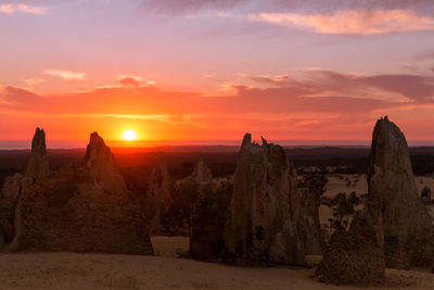 Panoramic view of rocks on landscape against sky during sunset