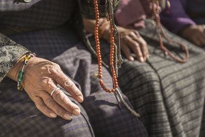 Midsection of women with necklace in sunny day