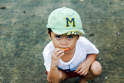 Portrait of boy eating food while crouching on road