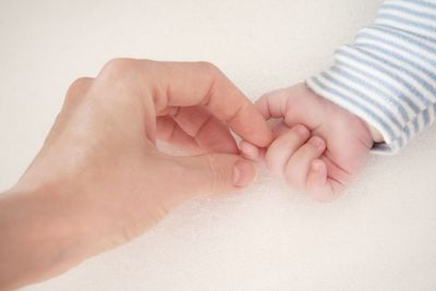 Low section of father holding baby hand