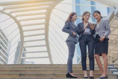 Low angle view of businesswomen using digital tablet while standing on steps