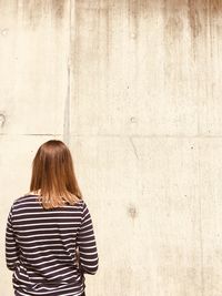 Rear view of woman standing against wall