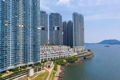 Modern buildings by sea against sky in city