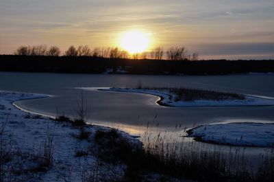 Scenic view of frozen lake against sky during sunset