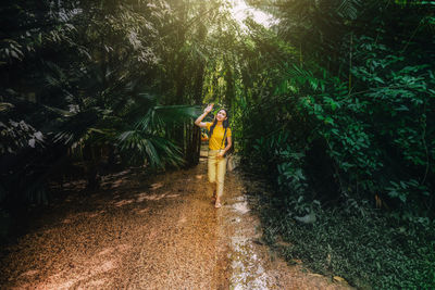 Woman walking amidst trees in forest