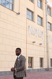 Man in suit standing against building