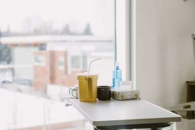 Items on bedside table in hospital room with window in background