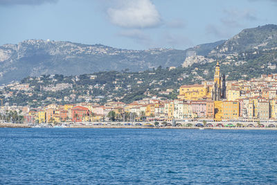 Aerial view of townscape by sea against sky