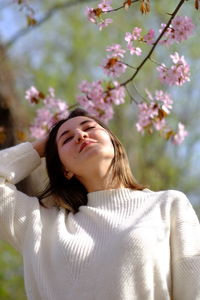 Low angle view of young woman with cherry blossom