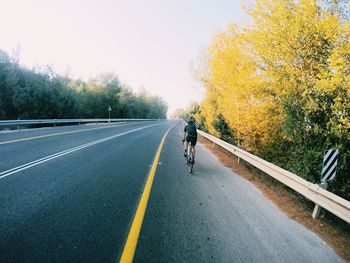 Side view of person walking on road along trees