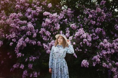 Woman standing by pink flowering plants