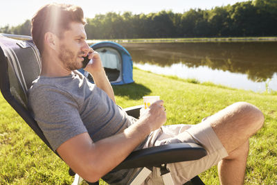 Midsection of man sitting by lake