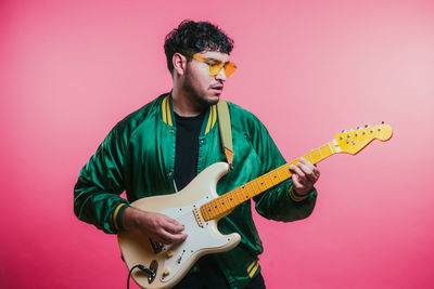 Man playing guitar against yellow background