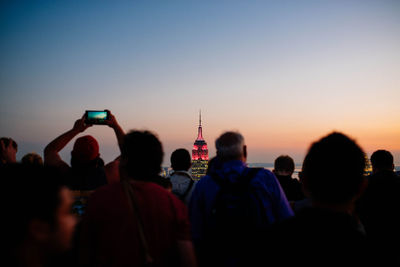 People on street against sky during sunset