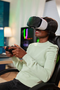 Smiling woman playing game while wearing virtual reality simulator