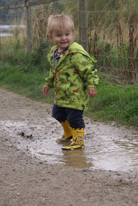 Boy playing in puddle on pathway