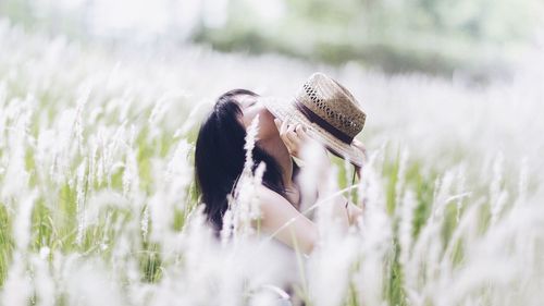 Woman with hat sitting on field