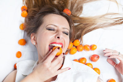 Directly above shot of young woman eating fruit while lying on white background