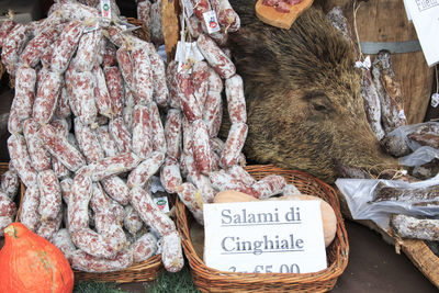 Salami for sale by dead wild boar at market