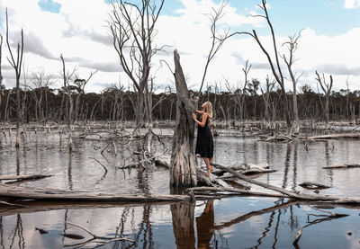 Woman standing by lake against sky