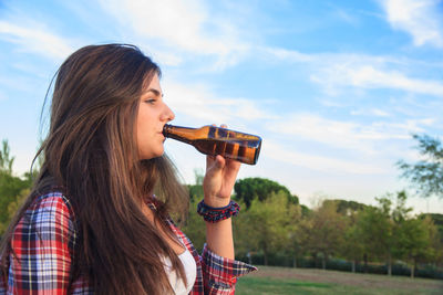 Portrait of woman photographing against sky