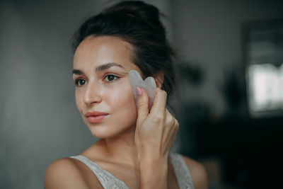 Brunette woman 30 years old doing face massage with a gouache scraper