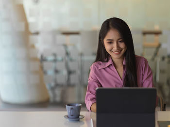 Businesswoman using digital tablet on desk in office