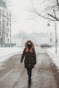 Woman with face mask walking outdoors in snow