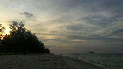 Scenic view of beach against sky at sunset